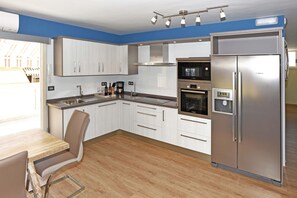 A modern kitchen with white cabinets, a Bosch refrigerator, and a built-in oven. - Apartamento Sabino en Puerto Naos (Puerto Naos)