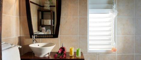 A bathroom with a white sink, a mirror with a wooden frame, and a window with blinds.