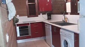 Een kleine keuken met een wasmachine, een koffiezetapparaat en een spoelbak.