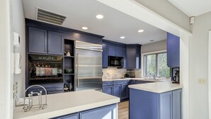 Una cocina moderna con armarios azul oscuro, electrodomésticos de acero inoxidable y una isla grande.