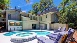 Una casa de dos pisos con piscina, mobiliario exterior y zona de barbacoa.