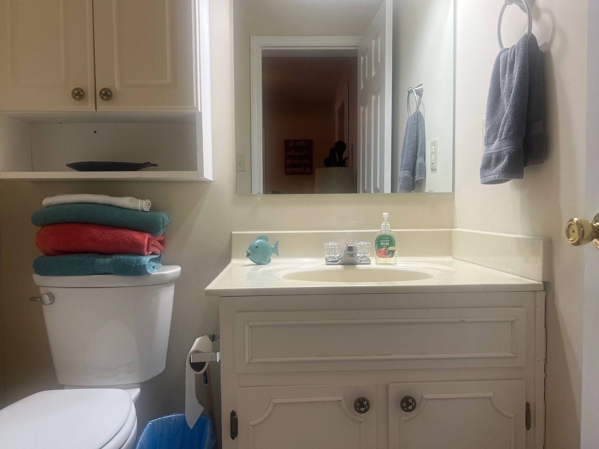 Une salle de bain comprenant des toilettes, un lavabo avec un distributeur de savon et un miroir au-dessus du lavabo.