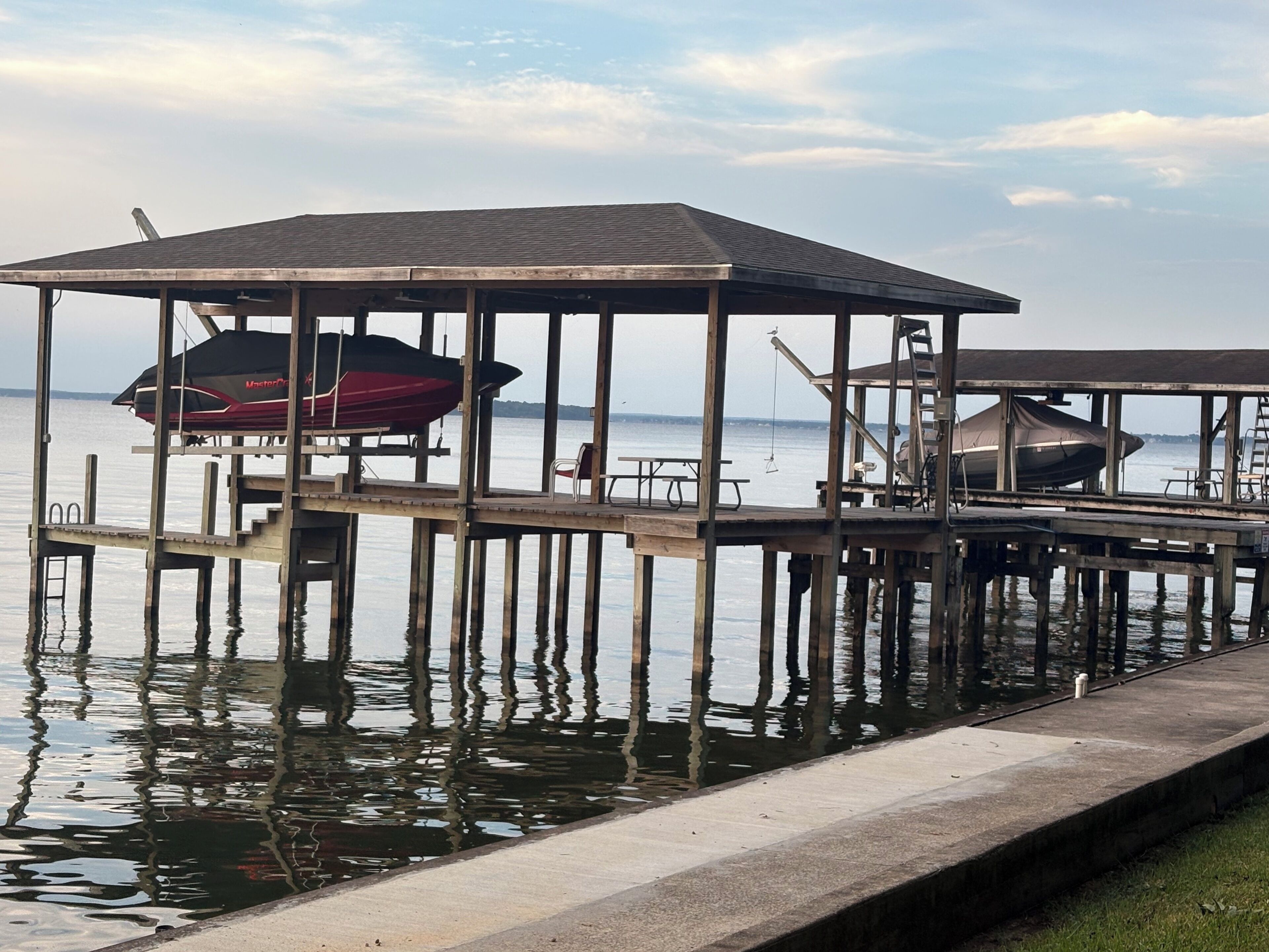 A pier with a covered seating area and a boat docked underneath.