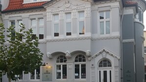 Ein historisches Gebäude mit einer symmetrischen Fassade, großen Fenstern und einem zentralen Eingang.