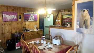 A dining area with wooden walls, a chandelier, and a table set for four with chairs.