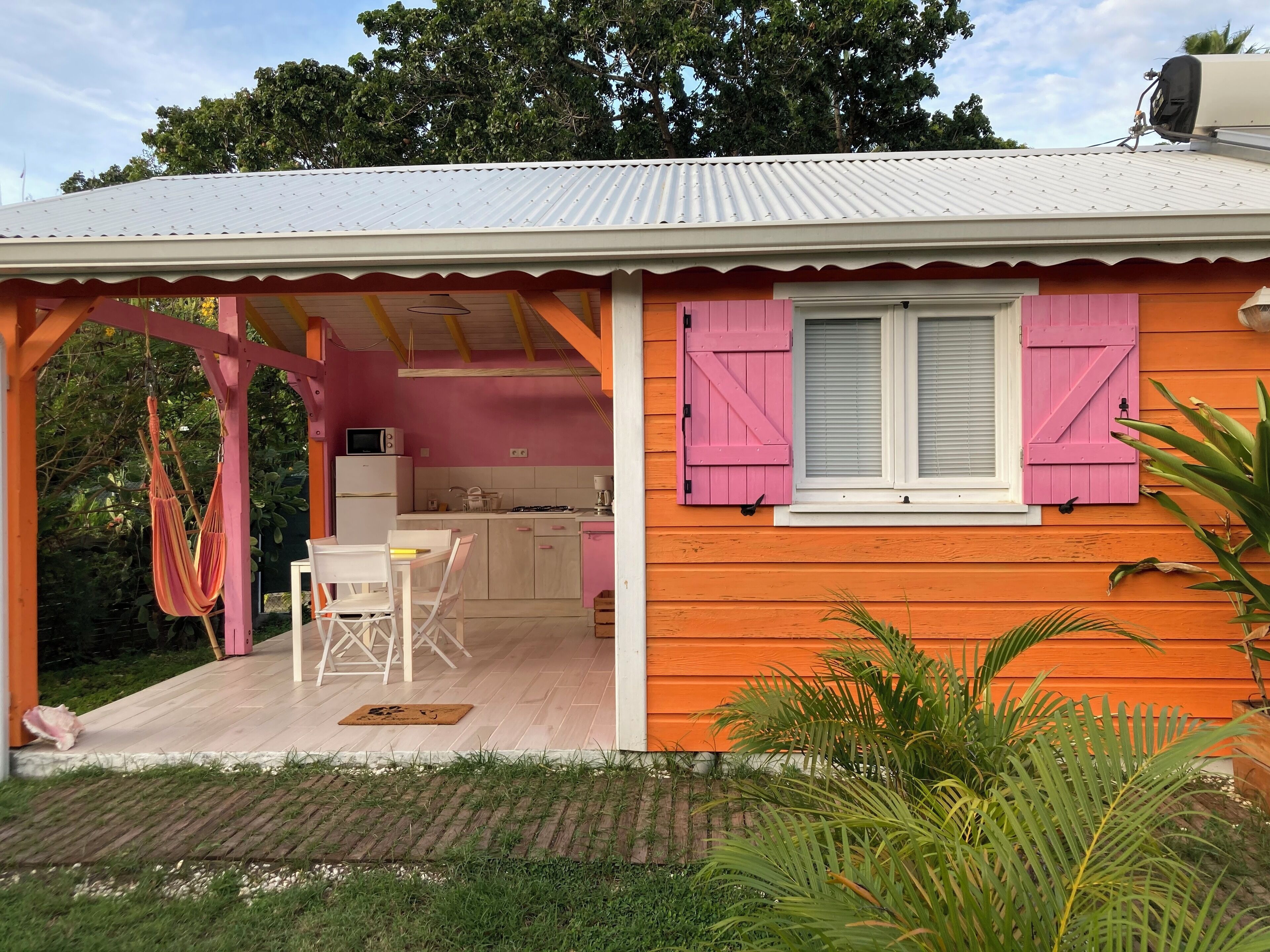 A cozy cottage with a kitchen and dining area, featuring a hammock and a small table.