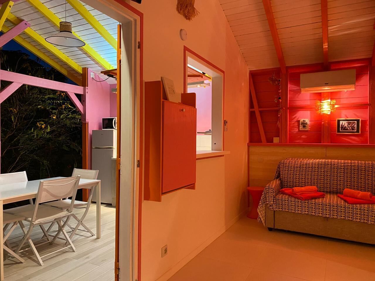 A cozy room with a dining area, a sofa, and a kitchen visible through an open door.
