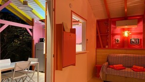 Ein gemütliches Zimmer mit Essbereich, einer Couch und einer durchgehenden Tür erkennbaren Küche.