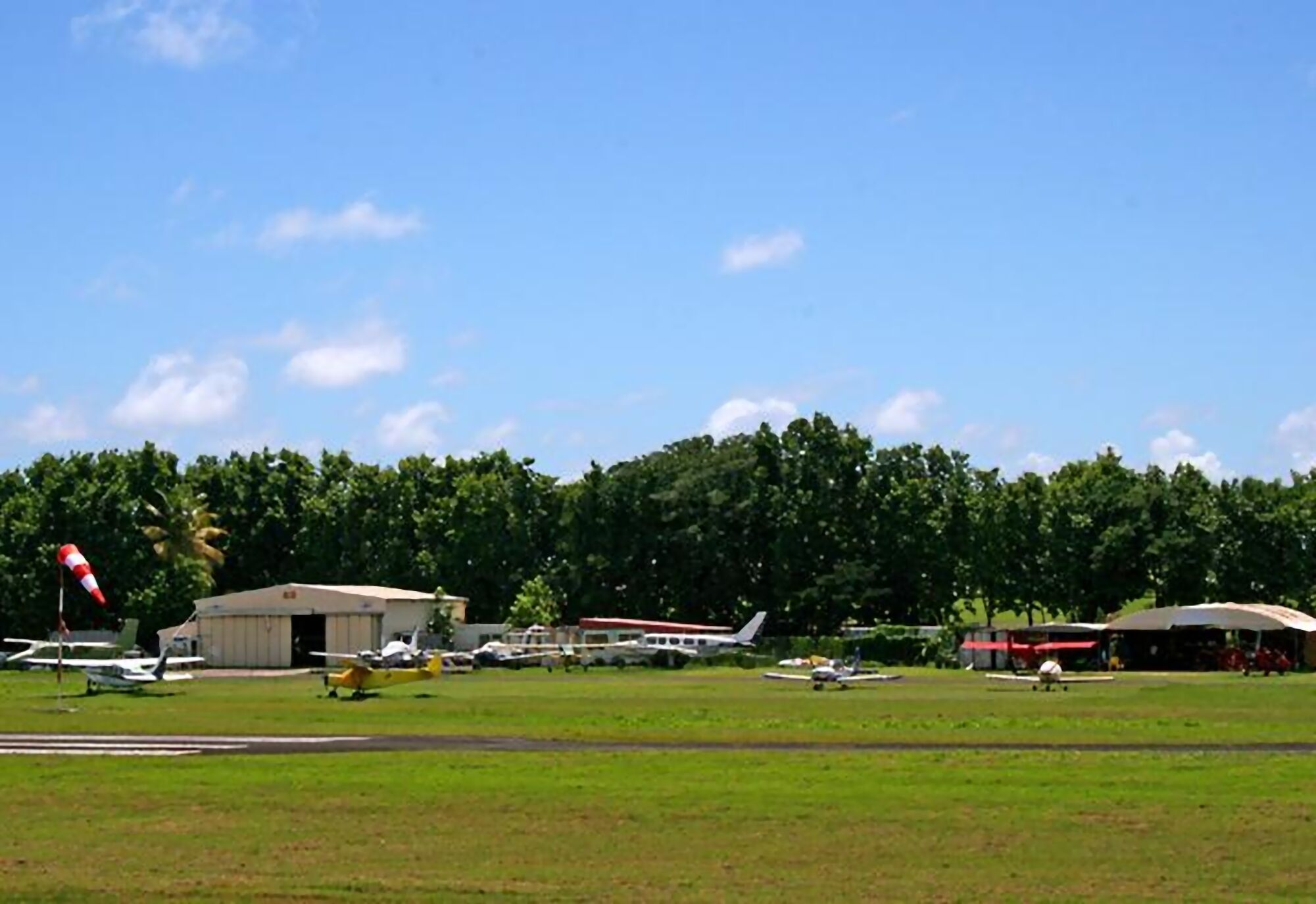 An airport with multiple aircraft parked on the tarmac, surrounded by lush green trees.