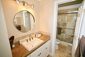 A bathroom with a sink, mirror, and shower area.