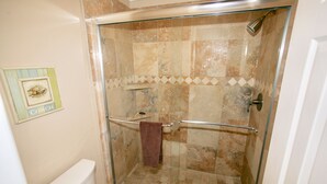 Een douche met glazen wanden, een glazen deur, een handdoekhouder en een douchekop.