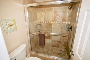 A glass-enclosed shower with a glass door, a towel rack, and a showerhead.