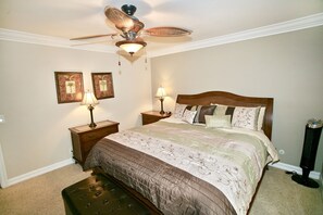 A bedroom with a bed, two nightstands, a ceiling fan, and two wall-mounted lamps.
