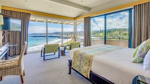Habitación de hotel con una cama grande, un escritorio, una silla y vistas al océano.