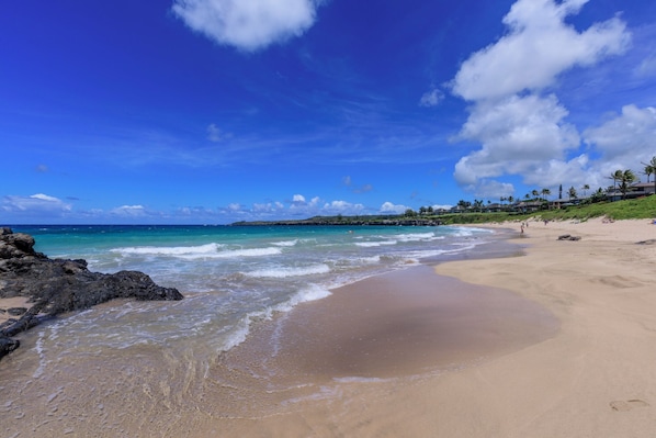 Enjoy a serene beach experience with gentle waves lapping onto the shore.