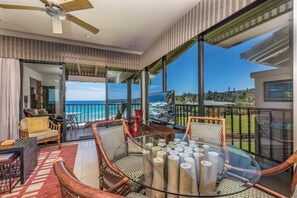 Enjoy a panoramic ocean view from this open-plan living area featuring a glass dining table and wicker furniture.