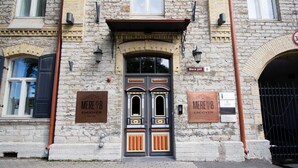 A historic building with a stone facade, a decorative double door, and two plaques on either side of the door.