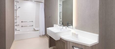 A modern bathroom with a walk-in shower, a double sink vanity, and a large mirror.