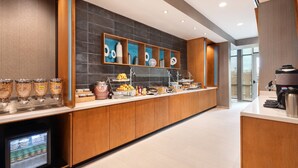 A modern hotel breakfast area with a long counter, various food dispensers, and a coffee machine. - SpringHill Suites by Marriott Tifton (Tifton)