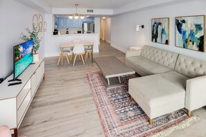 A modern living room with a sofa, TV, dining table, and chairs.