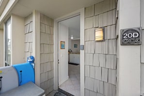 A residential entryway with a wooden exterior, a number sign '20D', and a surfboard leaning against the wall. - Beachfront cottage, Ocean & Sand Views. D20 North Coast Village (Oceanside)