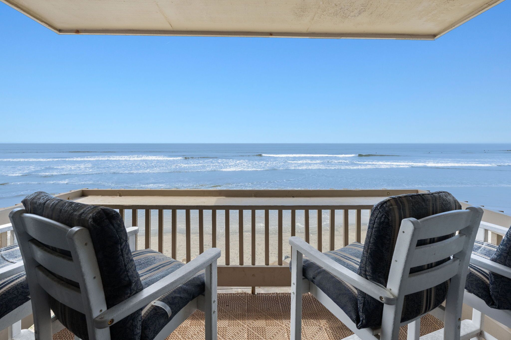 Un balcon avec deux chaises donnant sur l’océan.
