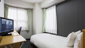 A hotel room with a bed, a desk, and a television displaying a cityscape.