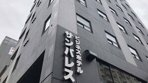 A tall building with a modern architectural design, featuring multiple windows and a prominent sign with Japanese characters.