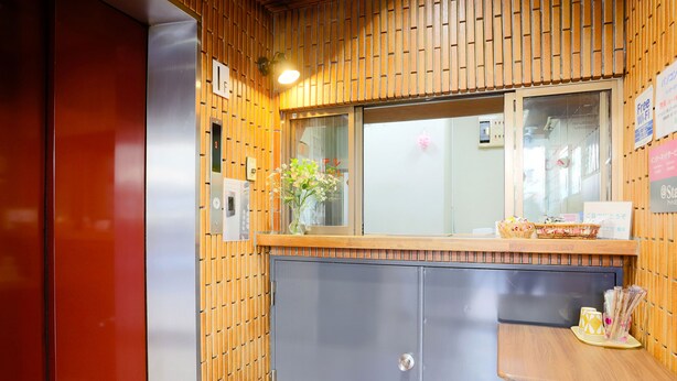 A reception area with a wooden panel wall, a reception desk, a window, and a door.