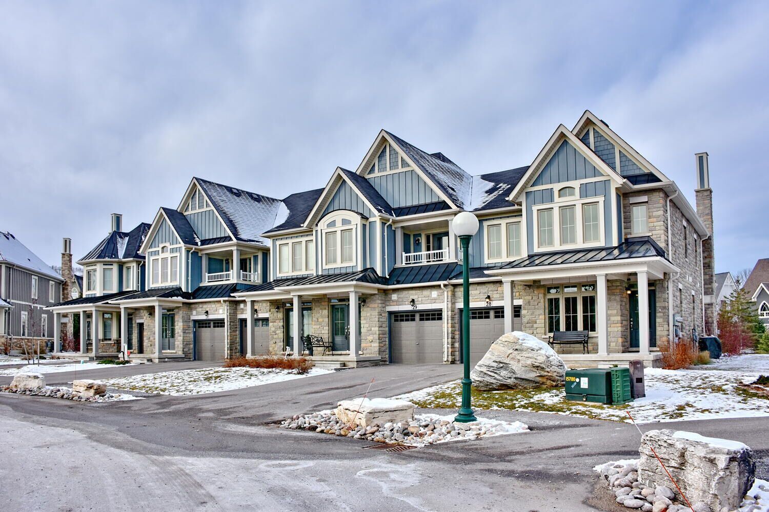 A row of modern two-story houses with stone facades, large windows, and attached garages.
