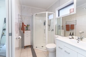 Een bad/douchecombinatie, een bubbelbad, een haardroger, handdoeken