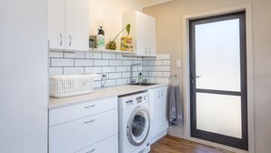 A compact laundry room with a washing machine, a sink, and a drying rack.