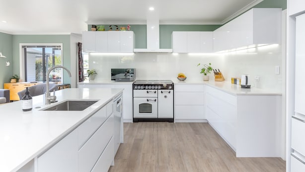 A modern kitchen with white cabinetry, a central island, and a built-in oven.