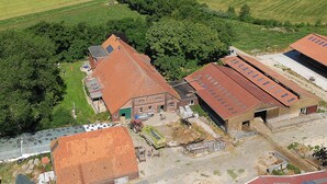 Luchtbeeld van een landgoed met meerdere gebouwen, waaronder een schuur en een huis met een rood dak.