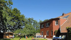 Een bakstenen huis met een verzorgd gazon, een schommel en tuinmeubilair.