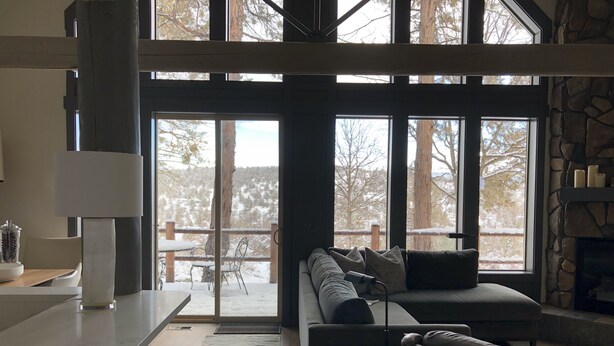 A modern living room with a large window, a stone fireplace, and a cozy seating area. - Renovated  Running Y Ranch Resort Home (Klamath Falls)