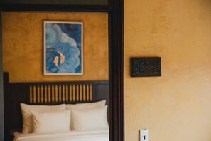 Une chambre d’hôtel avec un lit, un tableau au mur et une pancarte indiquant le numéro de la chambre.