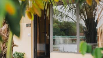 A glass door leading into a room with a view of a bridge and palm trees.
