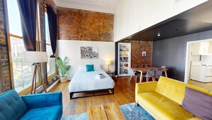 Una habitación moderna con una cama, una mesa de comedor y un sofá amarillo.