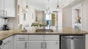 Une cuisine moderne dotée de plans de travail en granit, d’appareils électroménagers en acier inoxydable et de meubles blancs.
