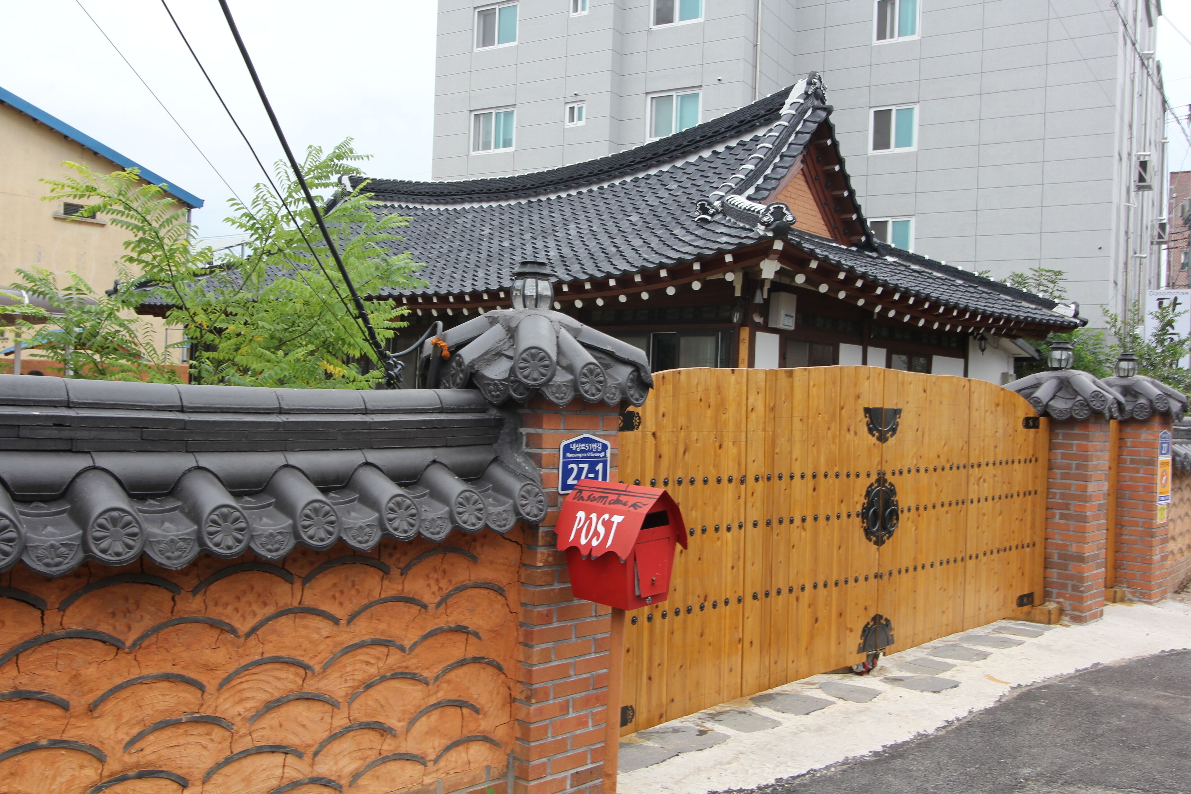 A traditional Korean gate with a red mailbox labeled "POST" and a blue sign with the number "271".