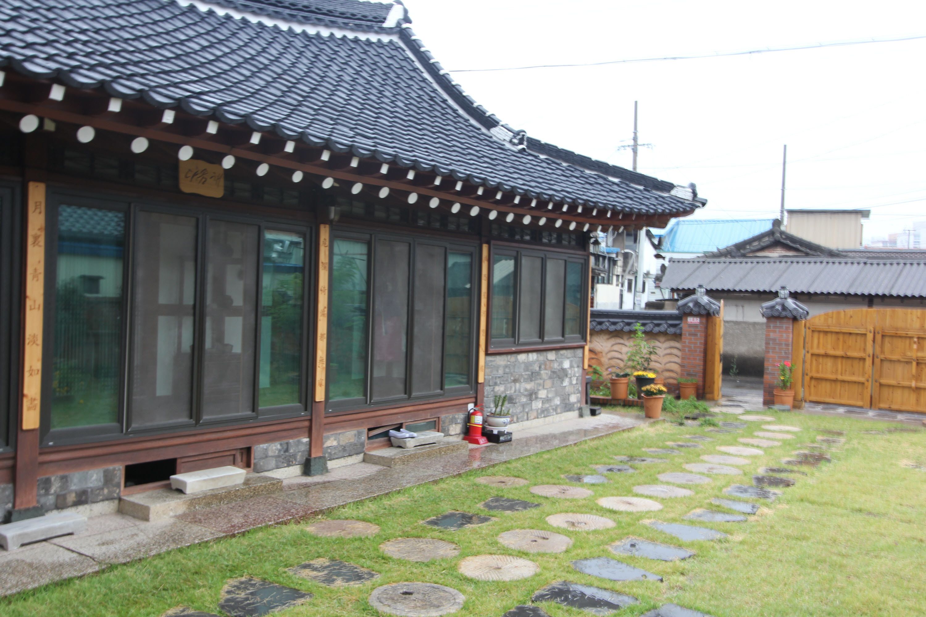 Un bâtiment traditionnel japonais, doté d’un toit recouvert de tuiles, de grandes fenêtres et d’un chemin de pierre menant à une porte en bois.