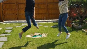 Two people jumping in a grassy yard with a wooden fence and a building in the background.
