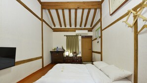 Une chambre avec un plafond en bois, un lit avec une literie blanche, une commode et un miroir.
