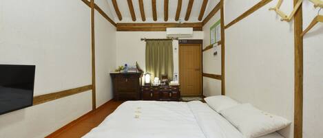 Un dormitorio con techo de madera, una cama con ropa de cama blanca, un aparador y un espejo.
