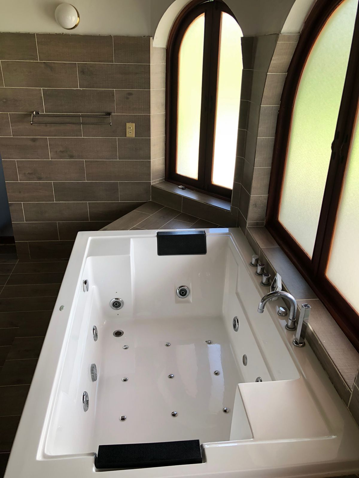 Un baño moderno con una bañera grande, una ventana con vidrio esmerilado y un perchero para toallas.
