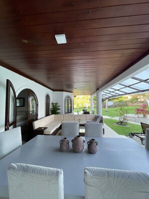 A covered outdoor seating area with a table, chairs, and three vases. - Super House for Vacation Group (Sosúa)