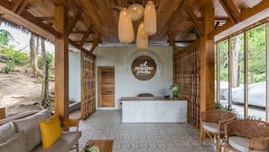 A reception area with a wooden ceiling, a reception desk, a sofa with cushions, wicker chairs, and a patterned floor. - Princess Paradise Koh Phangan (Ko Pha-ngan)