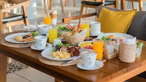 A breakfast table with plates of eggs, bacon, and toast, accompanied by orange juice and coffee cups. - Princess Paradise Koh Phangan (Ko Pha-ngan)