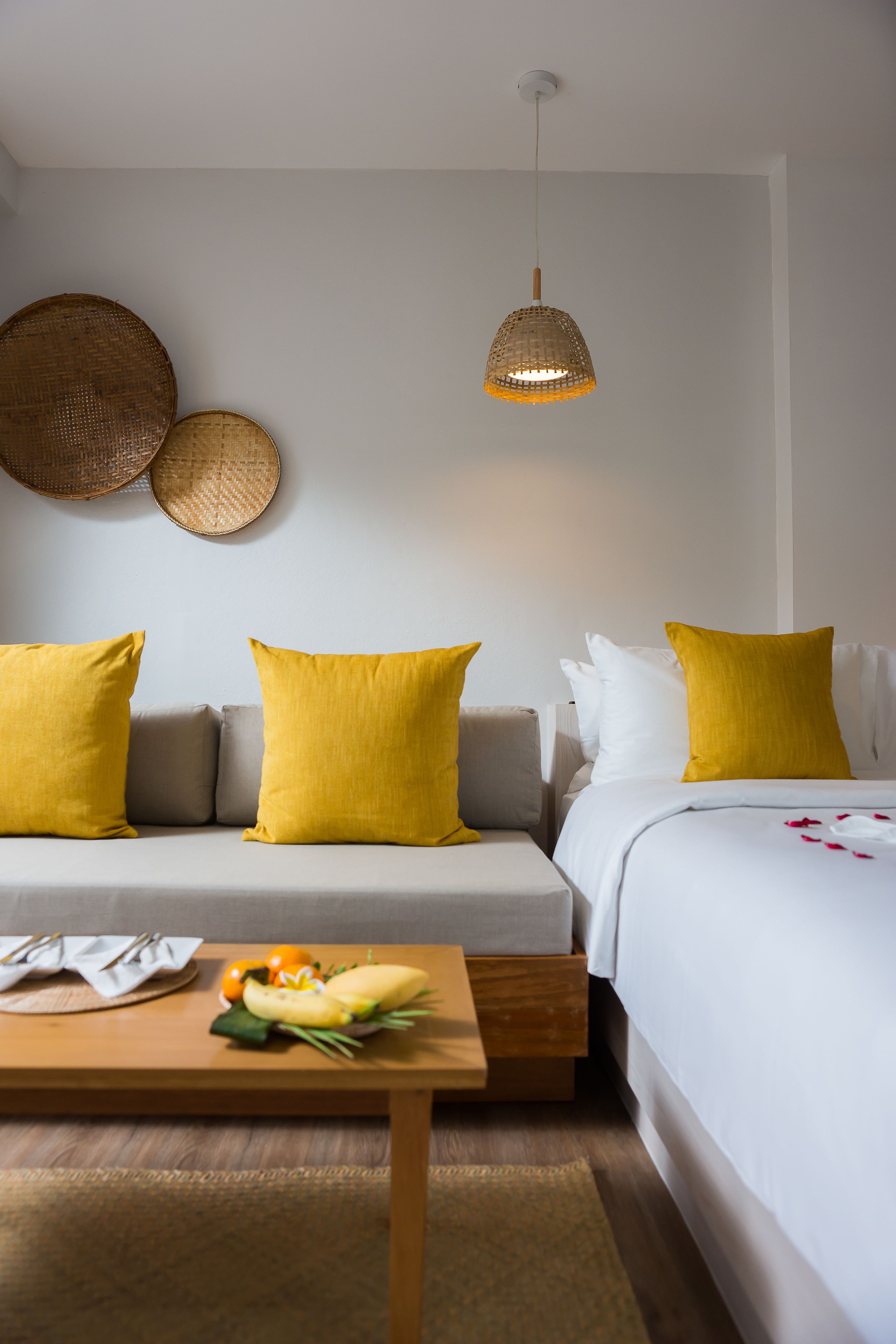 Ein Zimmer mit einer Couch, einem Bett, einem Holztisch und einer Pendelleuchte.